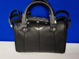 un sac à main en cuir noir posé sur une table blanche