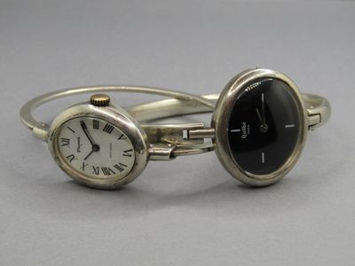 une paire de montres-bracelets en argent avec des chiffres romains et un cadran noir