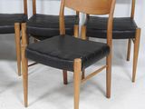 four chairs with black leather seats in a row against a white wall