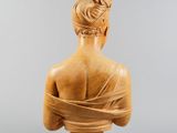 a wooden bust of a woman with a scarf around her neck