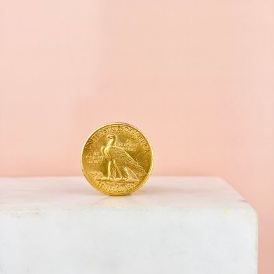 gold coin sitting on top of a white marble block