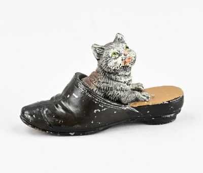 black leather clogger with a cat figurine on top of it