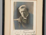 an old photo of a man in a suit and tie sitting in a chair