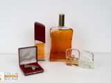 un flacon d'eau de Cologne à côté d'une boîte à bague et d'un coffret de parfum