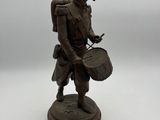 statue of a man with a drum and a hat on a white surface