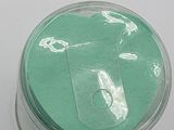 a jar with a green substance in it on a white surface