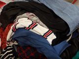 a pile of clothes sitting on a bed next to a laptop