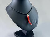 necklace with a red chili on a black stand