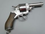 a silver revolver with a wooden handle on a gray surface