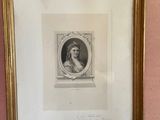 an old picture of a woman in a gold frame on a pink wall