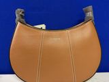 un sac à main en cuir marron muni d'une poignée en métal, posé sur une table blanche