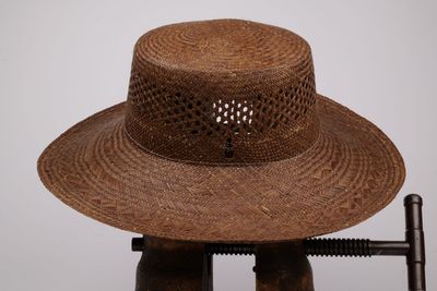 un chapeau marron posé sur un support, avec un pistolet à côté