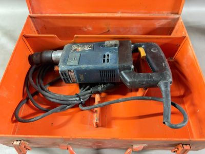 une boîte orange contenant une perceuse et un cordon d'alimentation