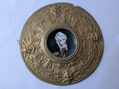 an image of a picture of a woman in a hat on a gold plate