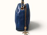 the small blue bag has a gold chain hanging from it ' s side
