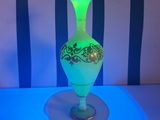 a green vase sitting on a table with a blue background