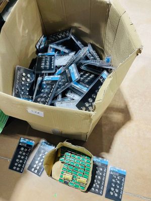 une boîte de télécommandes posée par terre à côté d'une pile d'autres télécommandes