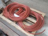 two red hoses sitting on a pallet next to each other