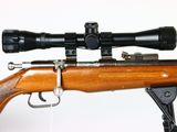 the rifle is on the stand with the scope on it ' s side