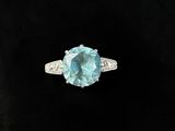 a close up of a ring with a blue topaz stone and diamonds