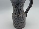 a small gray vase with a handle on a white table