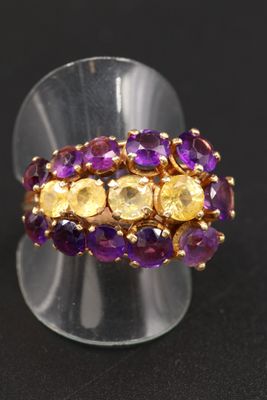 un gros plan d'une bague ornée de pierres violettes et jaunes