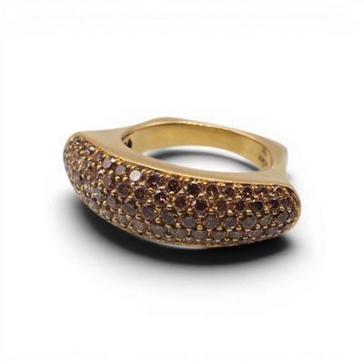 un gros plan d'une bague sertie de diamants bruns sur fond blanc