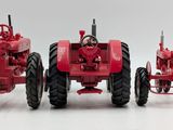 two red farm tractors sitting side by side on a white surface