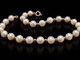 a close up of a bracelet with pearls on a black background