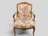 une chaise dont le dossier est recouvert d'un tissu à motifs floraux et dont la structure est en bois