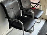 deux fauteuils en cuir noir placés l'un à côté de l'autre dans une salle d'attente