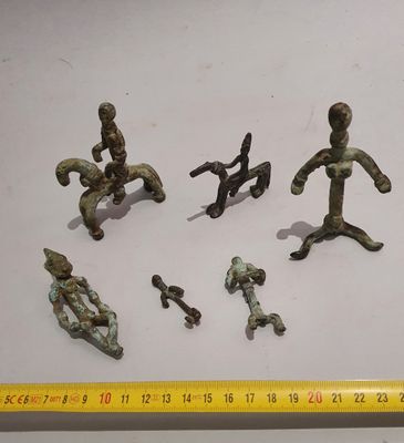 several figurines of different sizes and shapes are displayed next to a ruler
