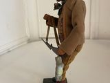 figurine of a man with a knife and a hat on a white surface