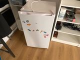 un petit réfrigérateur blanc dans le coin d'une pièce