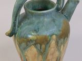 a blue and green vase with a handle on a white surface