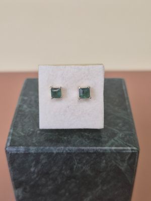 a pair of emerald earrings sitting on top of a marble block