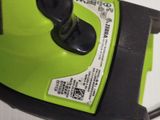 a close up of a green electric driller on a white surface
