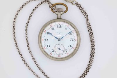 a silver pocket watch with a chain around it on a white surface