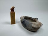 a small statue of a bird next to a small bowl