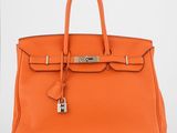 un sac à main en cuir orange muni d'un cadenas sur la poignée