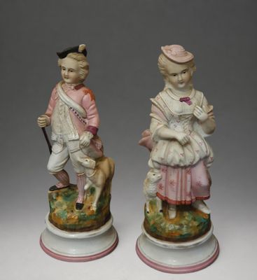 pair of porcelain figurines of a boy and a girl with a dog
