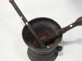 an old metal mortar and a wooden spoon on a white surface