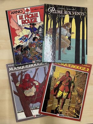 four comic books on a table with a clock in the background