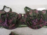 purple and green bralette and panties on a bed with a white background