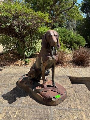 une statue représentant un chien assis sur un bloc de pierre