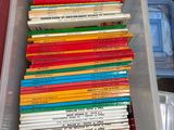 de nombreux livres dans un bac en plastique posé sur une table