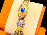 yellow gold ring with blue stones and diamonds on display on a wooden stand