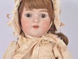 an antique porcelain doll of a young girl wearing a bonnet and dress