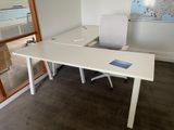 a white desk with a chair and a map on the wall