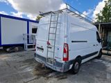 une camionnette blanche garée sur un parking, avec une échelle à l'arrière